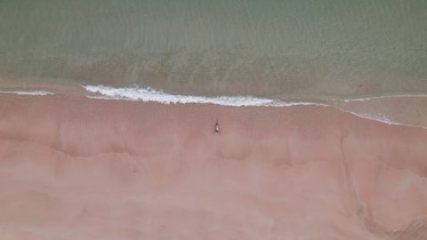Wide Overhead Drone Flight Towards Woman In Bikini Lying In Shallow Tide On Nacpan Beach, Palawan Island, Philippines