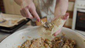 Woman prepares cabbage rolls. Close-up 4k video of housewife cooking tasty stuffed cabbages with minced meat. Home cooking process of healthy food. Preparing stuffed cabbage rolls