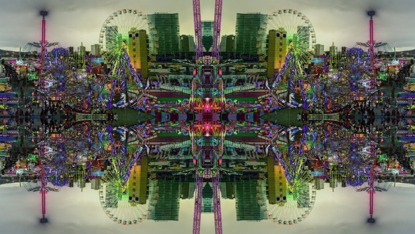 A timelapse of the lit up rides at a funfair in barcelona made into abstract mirrored pattern 