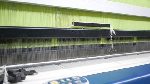 Weaving loom at a textile factory, closeup. Industrial fabric production line.
