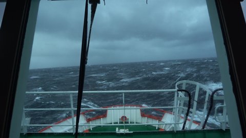 Ship in storm. Windscreen in water. View from bridge. Wave covers bridge. Ship climb up wave. A lot of splashes on windows. Strong pitching. High waves hit ship. White foam. Wave covers bridge