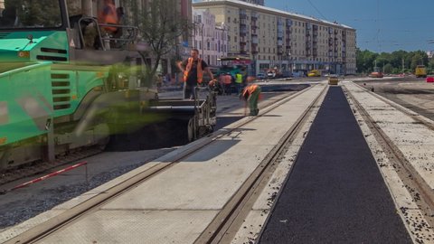 Workers operating asphalt paver machines and tippers during road construction and repairing works timelapse. Asphalt paver, roller and truck on the road repair site during asphalting