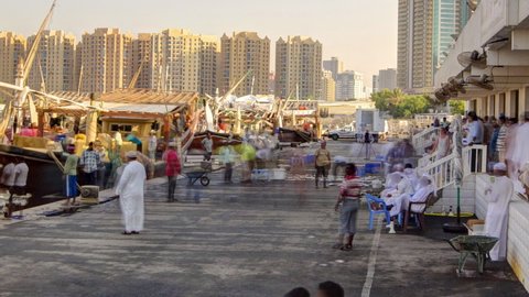 Seafood at the fish market in emirate of Ajman timelapse. Fishers sell many types of fises near boats. Towers on a background