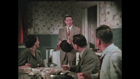 1950s: woman clicks film slate with "engagement", man in suit with hat in hand stands, talks to woman and men at kitchen table, man turns, leaves, woman smiles, talks, man eats with silverware