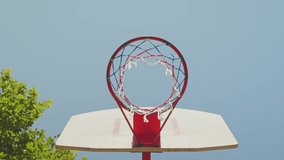 Basketball flying into the basketball hoop. Footage of a ball flying into the basket. Slow motion video from below the basket with the ball flying in. Goal.  