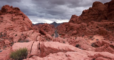 Fire Road is a popular spot for social media images in Valley of Fire State Park, Nevada, the road leading to the mountains in the background surrounded by bright red rocks and dark clouds moving