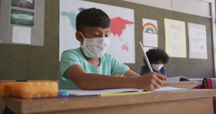 Animation of contour school items appearing over biracial boy in face mask at school. school, education and learning during covid 10 pandemic concept digitally generated video.