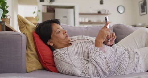 African american senior woman using digital tablet lying on the couch at home. retirement lifestyle living concept