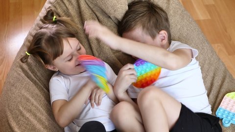 Boy and  girl play with a pop it touch toy. Brother and sister quarrel and fight.