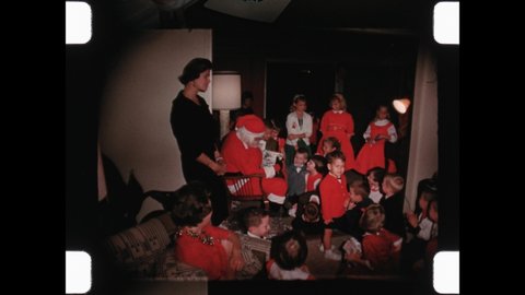 1957 Dallas, TX. Excited Kids wait in line to receive a gift from Santa Claus. Man in Santa Suit gives Children wrapped present while Mom and Auntie look on. 4K Overscan of Vintage Home Movies