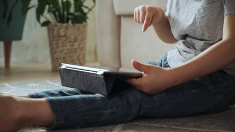 Child using tablet sitting on the floor at home, distance learning, e-learning, early child development