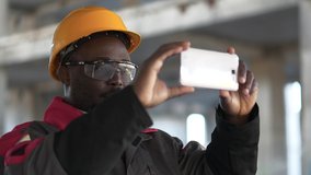 African american workman records videos on smartphone. Worker at construction site filming a video