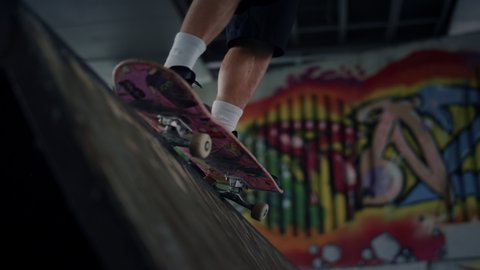 Active man practicing skateboard at skate park with graffiti on wall. Close up unknown male legs in sneakers riding on skate board outdoors. Recreation active leisure favorite hobby concept.  庫存影片