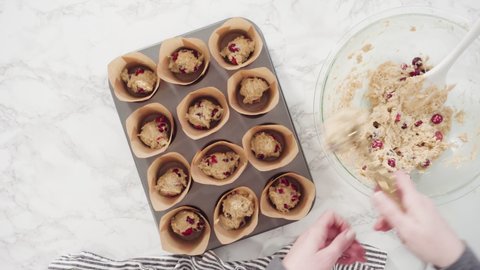 Flat lay. Step by step. Scooping dough into tulip muffin liners with mixture scoop to bake cranberry muffins.