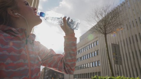 On a hot day, a girl drinks water from a plastic bottle.