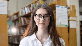 Portrait of a beautiful girl in glasses in the university library