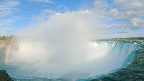 Niagara Horseshoe Falls with beautiful turquoise green blue water running down the cliff and big mist rising from Niagara River on a sunny day