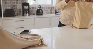 Video of midsection of african american woman unpacking groceries in kitchen. lifestyle, household, spending free time at home.