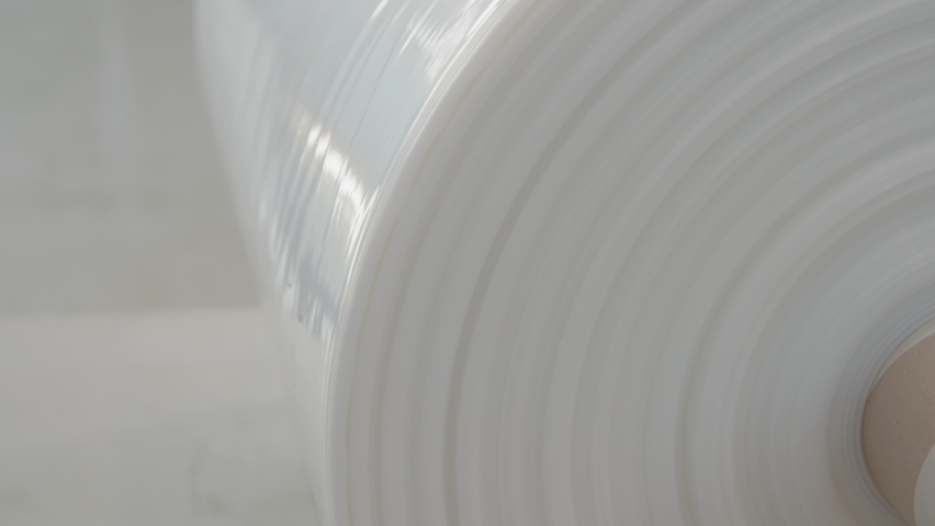 White plastic film roll close-up. Industrial plastic wrap and flexible packaging. Thermal laminating film. Factory use. Beautiful plastic product shot. Royalty-Free Stock Footage #1090242467