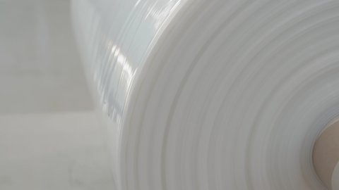 White plastic film roll close-up. Industrial plastic wrap and flexible packaging. Thermal laminating film. Factory use. Beautiful plastic product shot.