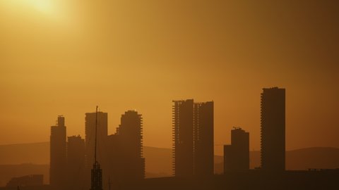 8K 7680x4320.Cloudless sunset through city skyscrapers.Time lapse clear and clean sky.High buildings in a new modern residential area.Silhouette of buildings.Urban metropolis background landscape awe.
