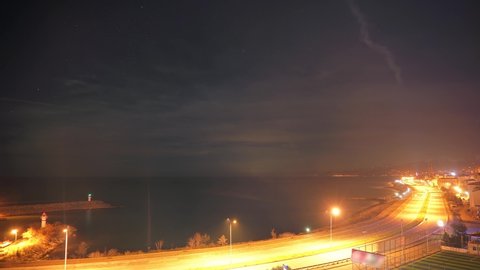 8K 7680x4320.Sunrise in the port of the city by the sea.Night to day transition effect.Time lapse in seaside.Highway road traffic cityscape way jetty mole lighthouse midnight at dawn twilight dusk 8K.