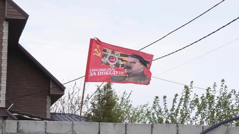 flag of the soviet union with a portrait of stalin hanging on the street. 4k footage. moscow russia 9 may 2022