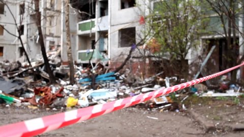 Enclosing red-white signal tape area near a destroyed residential building after the bombing of the Ukrainian city by Russian aircraft. Ruins of city Chernihiv of terrorist attacks, bomb shelling.