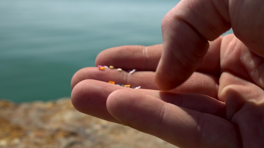 Close-up shot of microplastics particles on the fingers of a volunteer. The concept for water pollution and global warming. Climate change idea. Soft focus of micro plastic that cannot be recycled | Shutterstock HD Video #1090247597