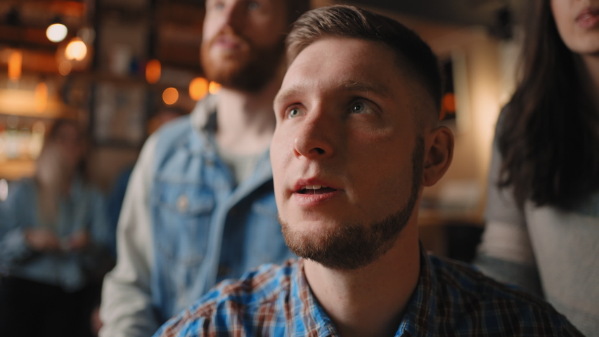 Portrait of a bearded male fan watching football in a bar with friends. football, hockey, basketball. Sports fans upset about favorite sports team losing match, watching game in pub Royalty-Free Stock Footage #1090248005