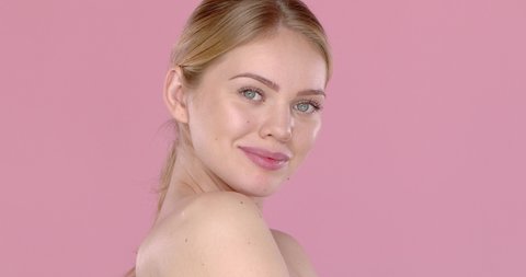 Slow motion video shot of happy beautiful girl, isolated on pink background. Side angle