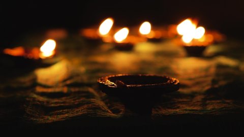 Diwali Diya oil lamps are placed on a table among other glowing Diya lamps  Decorative Diya lamps 