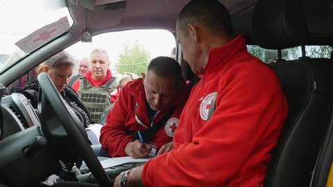 Kharkiv Kharkov region, Rogan, Ukraine - 05.10.2022: volunteer organization Red Cross supports people in difficult times war man writes list for issuance humanitarian aid for those in need donation