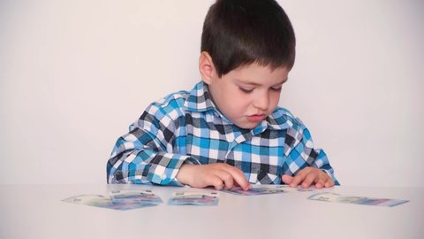 A 4-year-old boy counts money, holds euros in his hands. Teaching children financial literacy, pocket money.