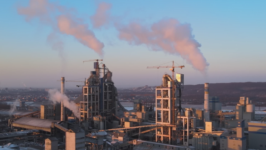 Aerial view of cement factory with high concrete plant structure and tower cranes at industrial production area. Greenhouse gas smoke polluting atmosphere. Manufacture and global industry concept. Royalty-Free Stock Footage #1090251511