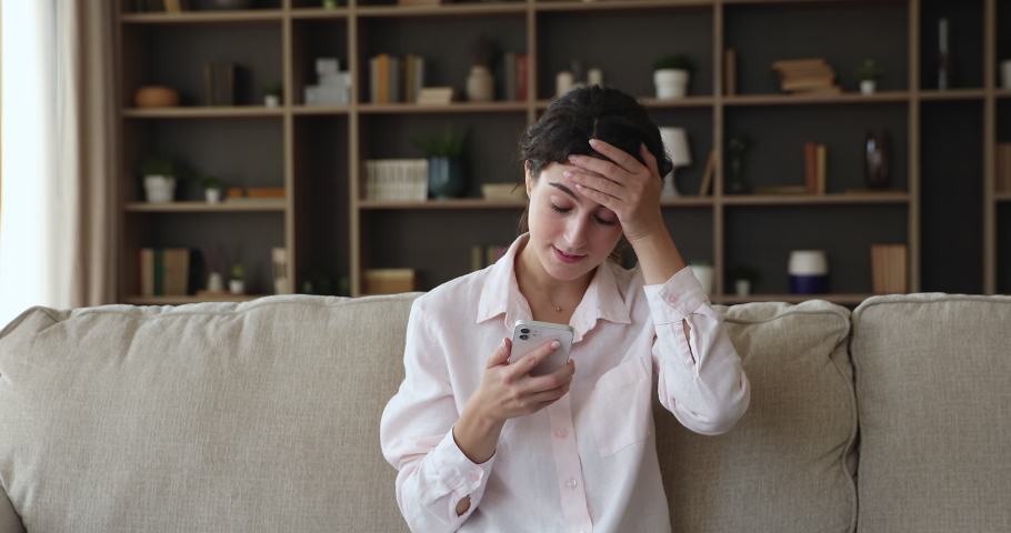 Young woman sit on sofa read sms with bad news looks annoyed, check calendar feels stressed due forgotten appointment or important missed call by work. Got negative notice, awful notification concept Royalty-Free Stock Footage #1090253167