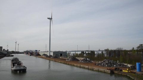 Genk, Limburg, Belgium - 04 12 2022 - Industrial activity and a windmill driven electronic plant at the banks of the Albert canal