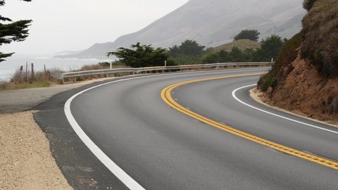 Pacific coast highway 1, Cabrillo road along ocean, foggy California, Big Sur, USA. Coastal road trip, traveling on car by sea. Cloudy misty weather. Yellow dividing line, asphalt. Turn of serpentine.