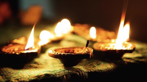 Diwali Diya oil lamps are placed on a table among other glowing Diya lamps  Decorative Diya lamps 