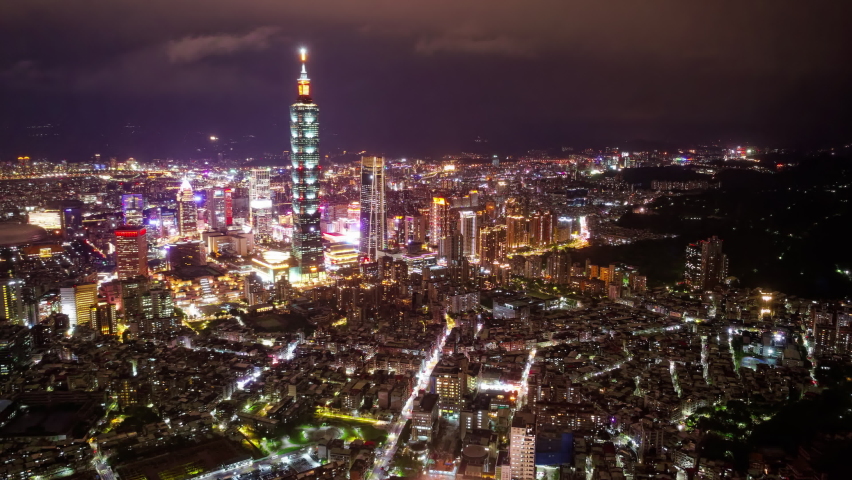Aerial hyperlapse of Downtown Taipei at night, the vibrant capital city of Taiwan, with 101 Tower standing out amid modern skyscrapers in XinYi Commercial District and city lights dazzling in the dark Royalty-Free Stock Footage #1090257917