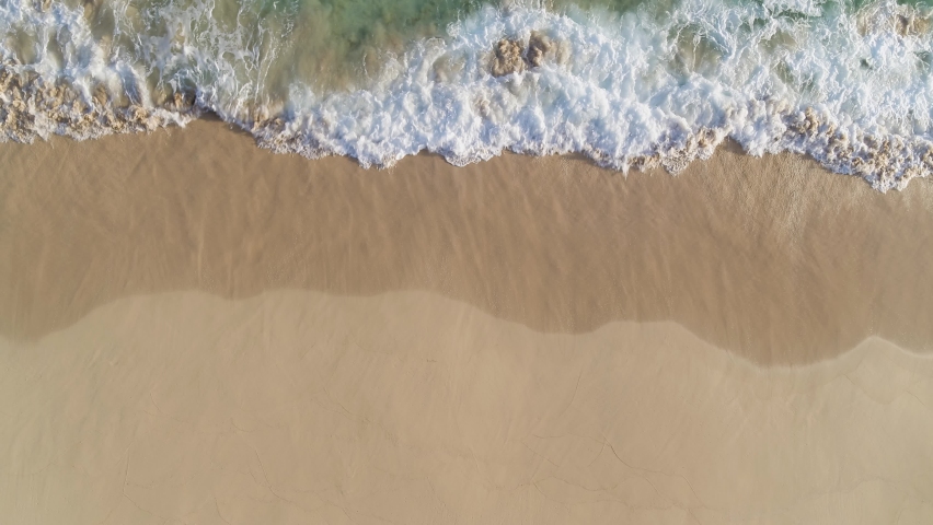 Sea wave on the sand of a tropical beach, top view. White pattern of sea foam on golden sand. Walk along the sea coast. Seascape. Rest on the sea. Royalty-Free Stock Footage #1090258535