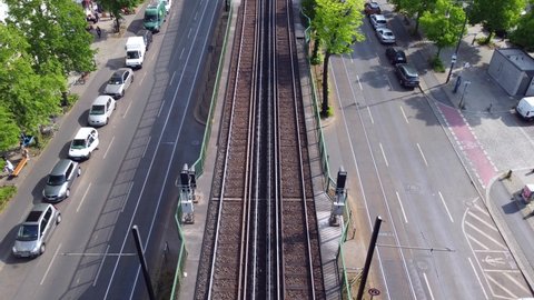 Yellow subway goes into the elevated train station Eberswalder. Marvelous aerial view flight track from above drone footage of Berlin Prenzlauer Berg Schönauer Allee 2022. Cinematic by Philipp Marnitz