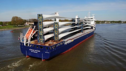 Barendrecht , Netherlands - 04 18 2022: Aerial Stern View Of Symphony Provider Cargo Ship Transporting Transporting Wind Turbine Propeller Blades Along Oude Maas 