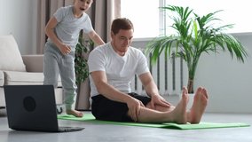 Father doing morning exercises while active energetic child son playing. father working and doing yoga exercise at home for stress relief relaxing with naughty little kid. video footage slow motion.