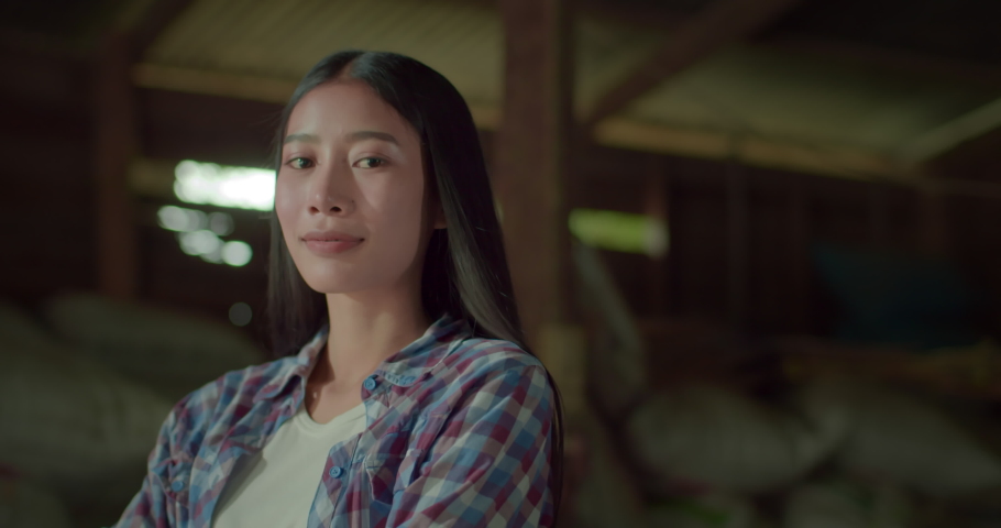 A happy smiling beautiful long-haired female Asian farmer who has a small family rice mill in a rural area.