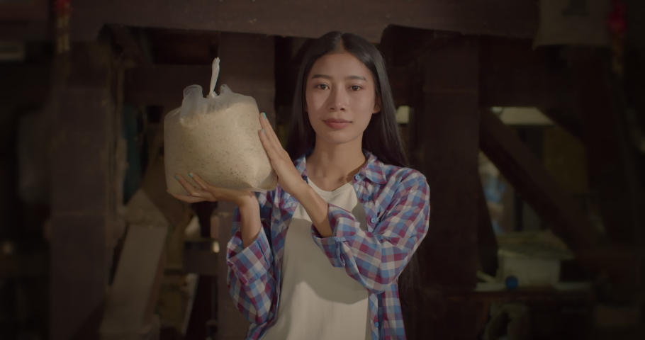 A happy smiling beautiful long-haired Asian farmer woman who has a small family rice mill in a rural area.