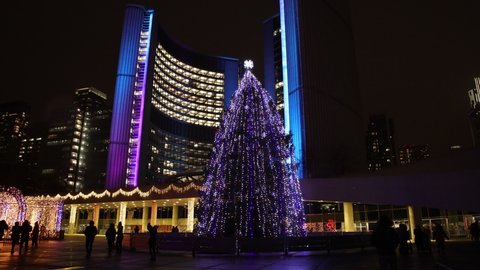 Toronto, Ontario, Canada - DEC 2021 -  Christmas Tree and Holiday Season Light decorations at Nathan Phillips Square in background of business and financial buildings