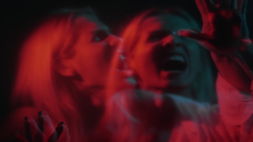 Scary horror. Spooky night. Screaming face. Defocused double exposure of afraid shouting trapped woman in red neon light on dark background. | Shutterstock HD Video #1090262109