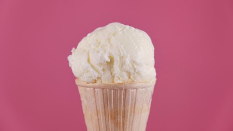 Vanilla ice cream in waffle cone melting on pink background. Timelapse of delicious white ice cream melting. Close-up of sweet dessert. 4K, UHD