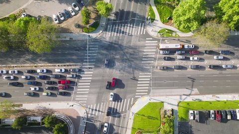 Aerial view of a downtown road intersection on a sunny day. Traffic signals give right to move during rush hour in a big metropolis. High quality 4k footage